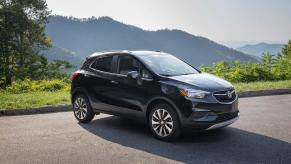 A dark colored Buick Encore with a moutntain behind.