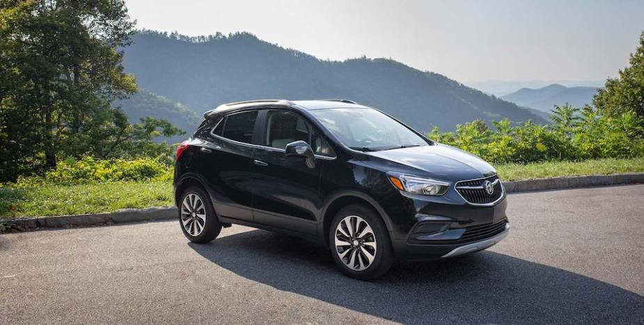 A dark colored Buick Encore with a mountain behind.