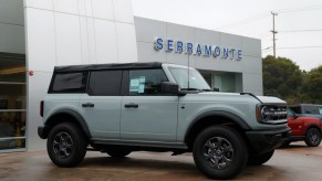 A gray Ford Bronco is parked outside of a dealership.