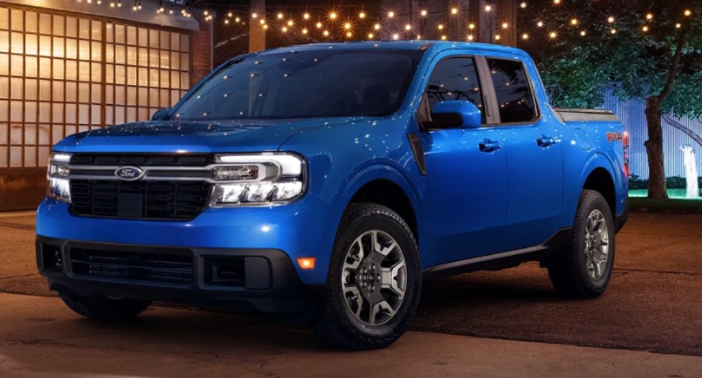 A blue 2022 Ford Maverick compact truck is parked outside of a home. 