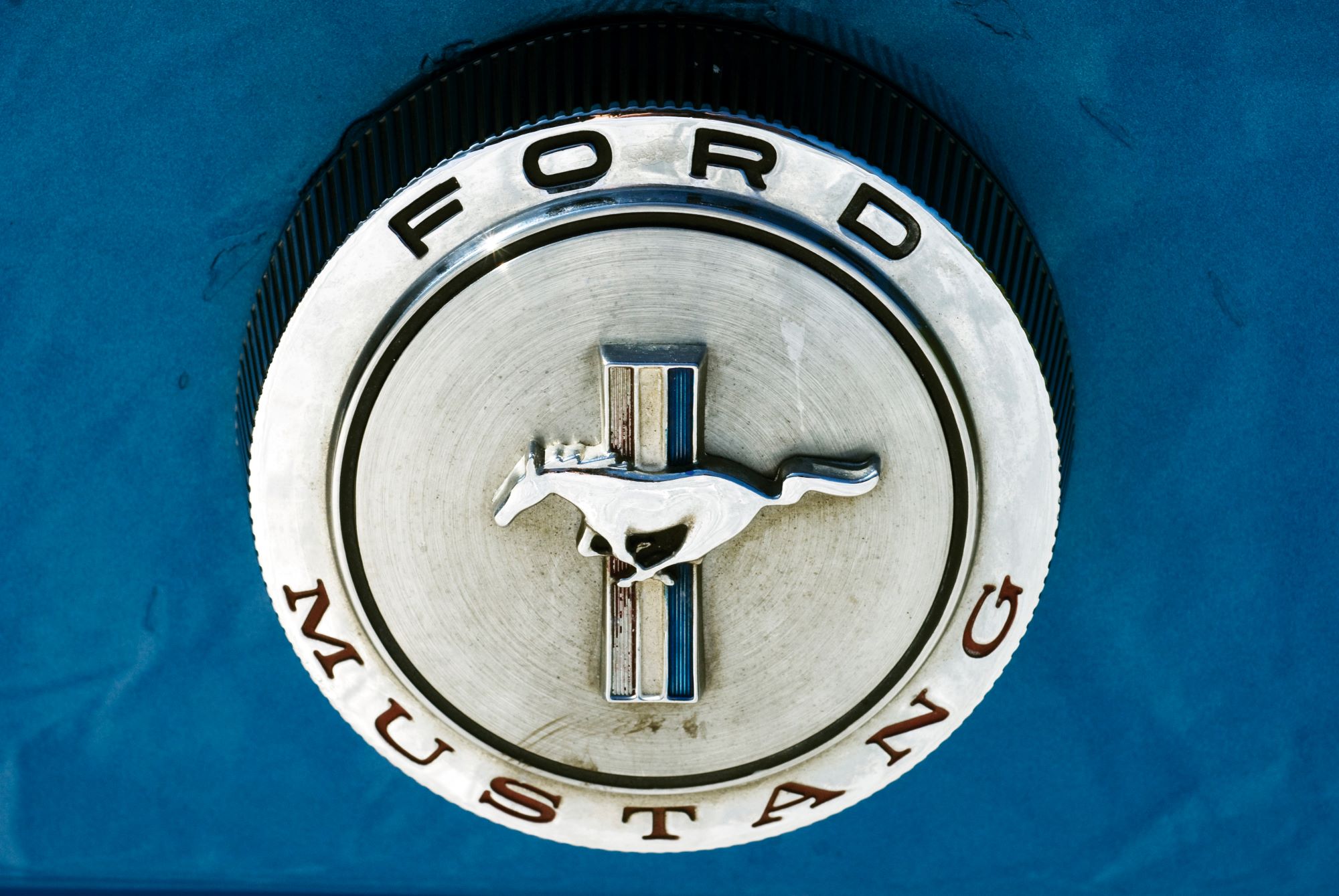 A silver Ford Mustang logo on a blue car.