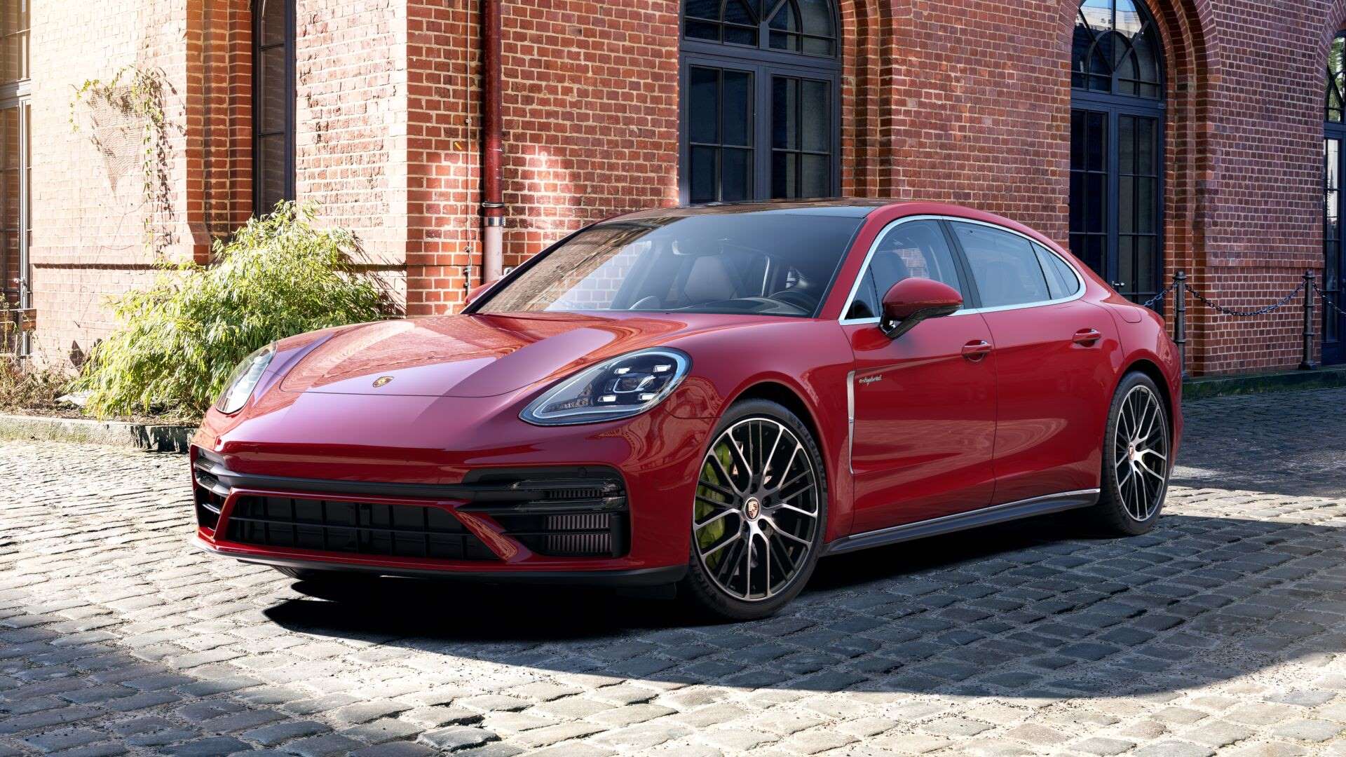Fully loaded new Carmine Red 2022 Porsche Panamera Turbo S E-Hybrid Executive parked next to a large brick building