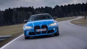 Fully loaded new blue 2022 BMW 4 Series M4 Competition xDrive Coupe driving on a racetrack