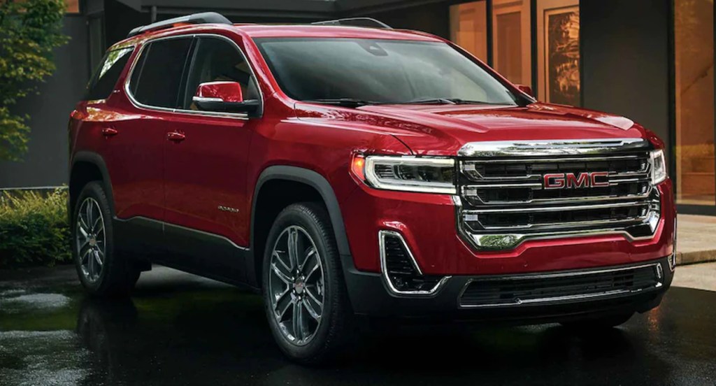 A red 2022 GMC Acadia SUV is parked outside a home.