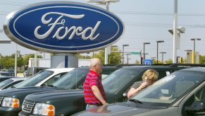Front of Ford dealership with new cars and Ford sign.
