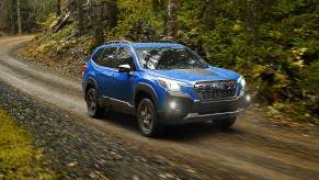 Geyser Blue 2022 Subaru Forester driving on a dirt road