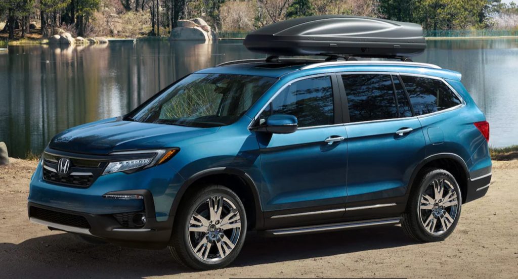 A blue 2022 Honda Pilot full-size SUV is parked by a body of water. 