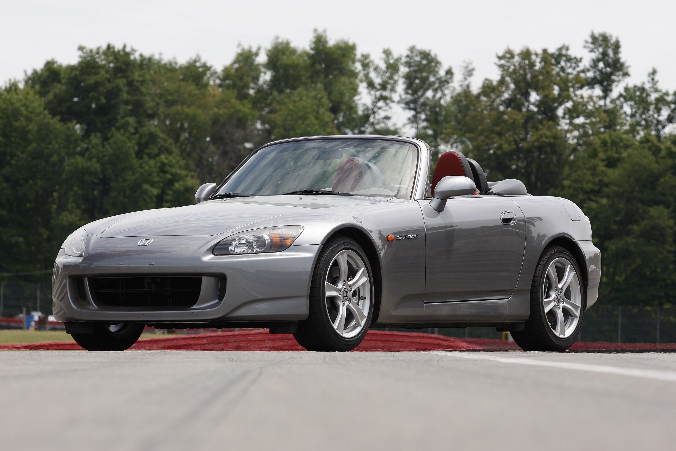 A grey AP1 generation Honda S2000 roadster shot from the front 3/4 at a race track