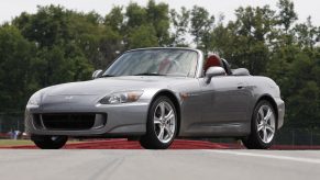 A grey AP1 generation Honda S2000 roadster shot from the front 3/4 at a race track
