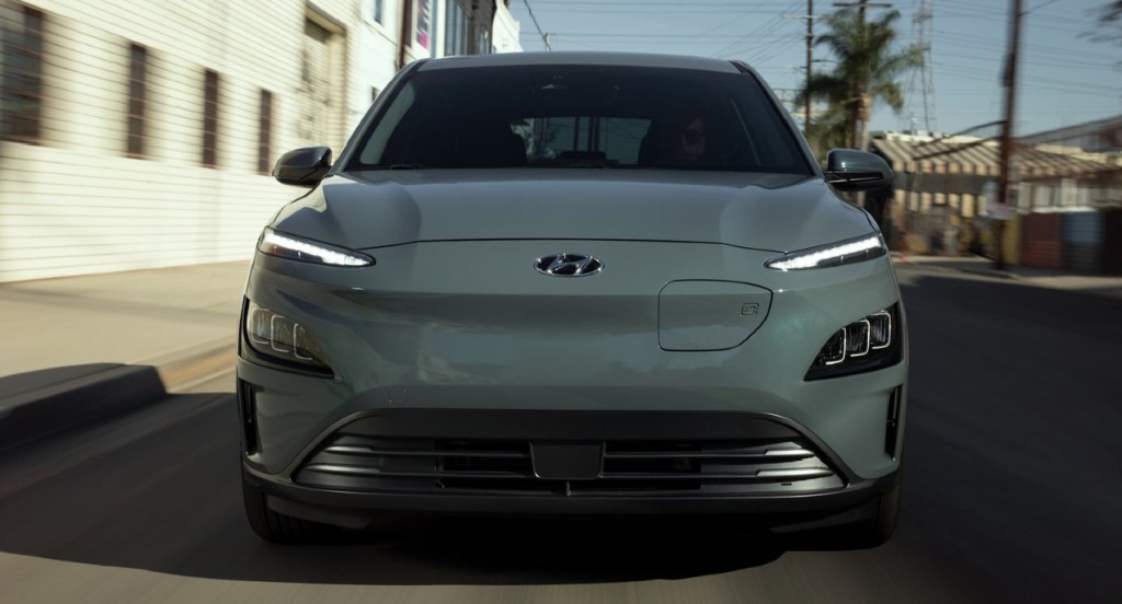 A gray 2022 Hyundai Kona Electric SUV is driving on the road.  
