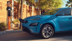 A blue 2022 Hyundai Kona Electric SUV is charging.