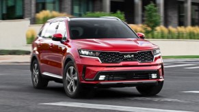 A red 2022 Kia Sorento Hybrid is driving in a parking lot.