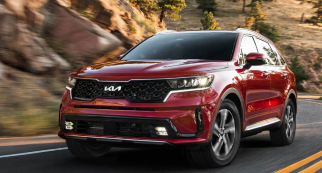 A red 2022 Kia Sorento Hybrid is driving down the road.