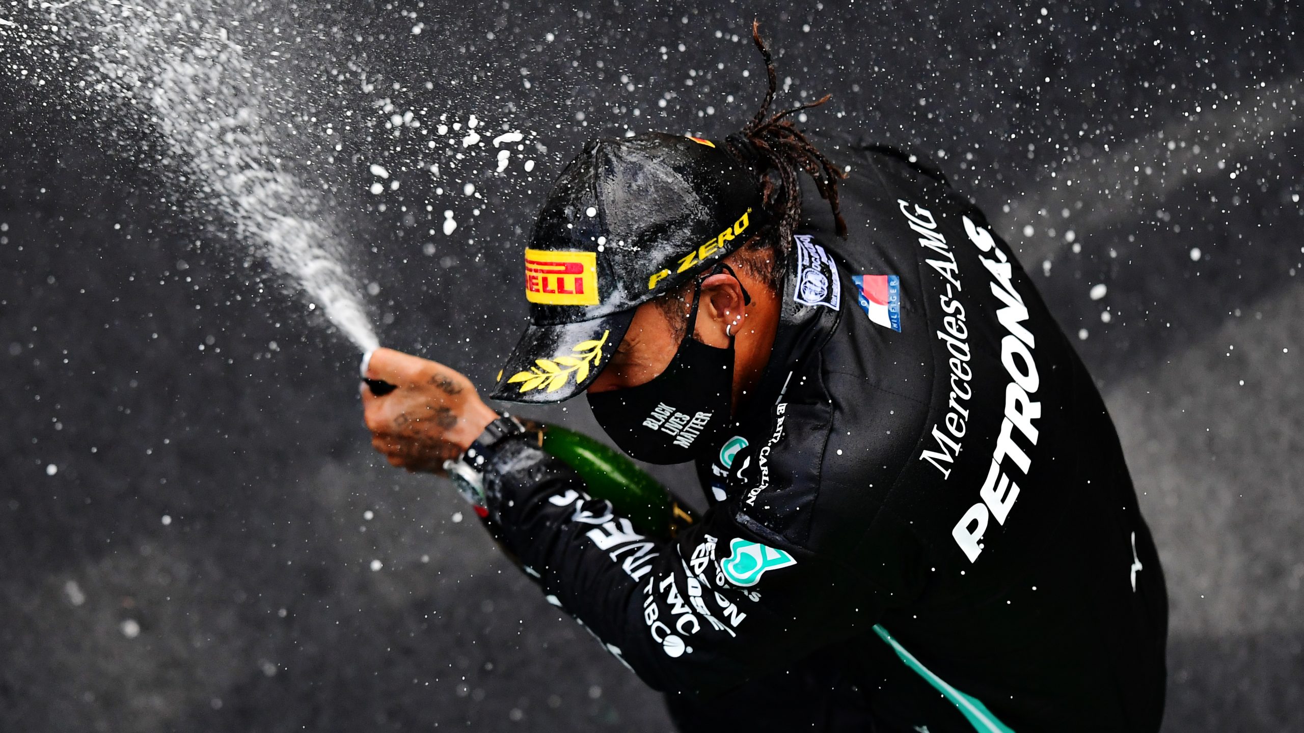 Professional racing driver Lewis Hamilton celebrates a Formula 1 victory with champagne on the podium