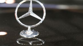 Silver standing Mercedes-Benz logo on top of a black car.