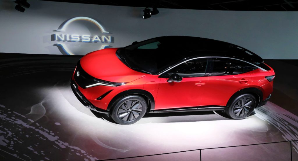 A red Nissan Ariya electric SUV is on display.