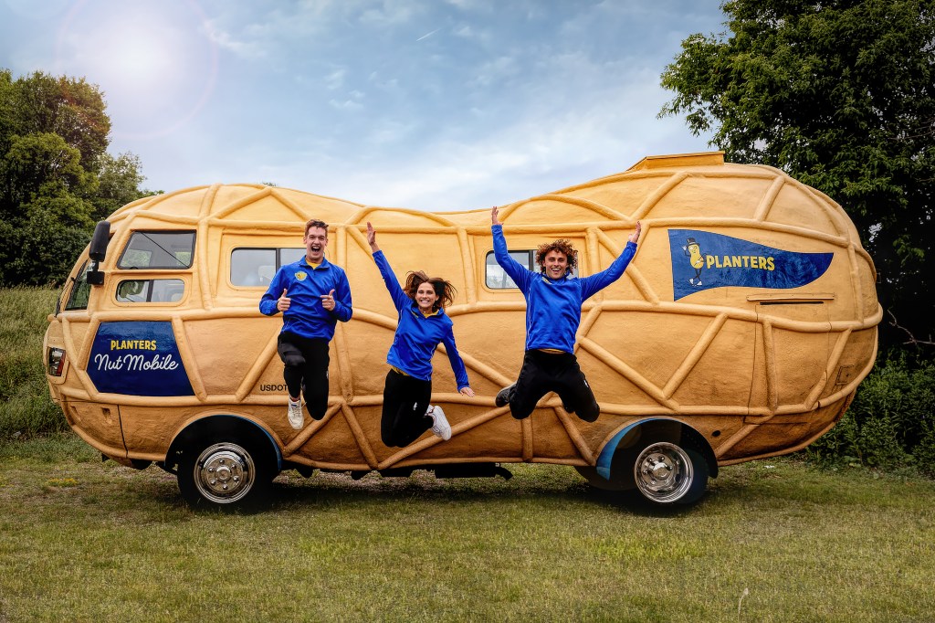 Three Peanutters jump for joy in front of the Nutmobile.