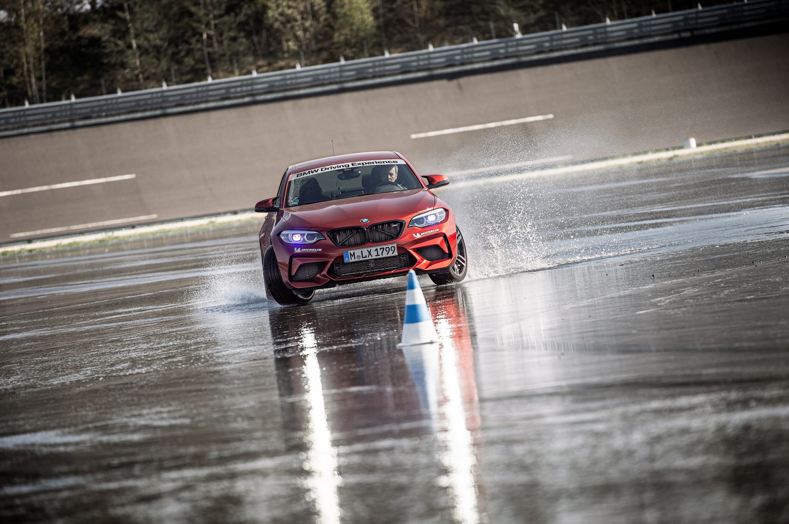 A driver at a performance driving school practices a controlled slide in a BMW M2