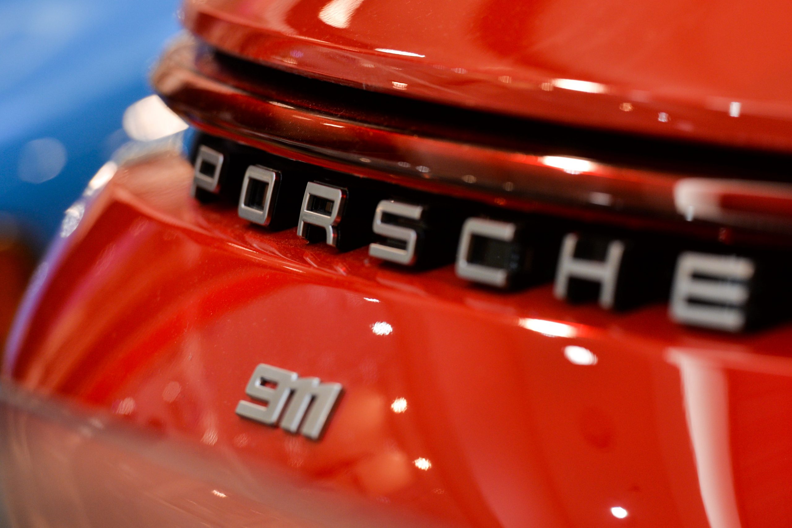 A Porsche 911 logo on the back of a red car. 