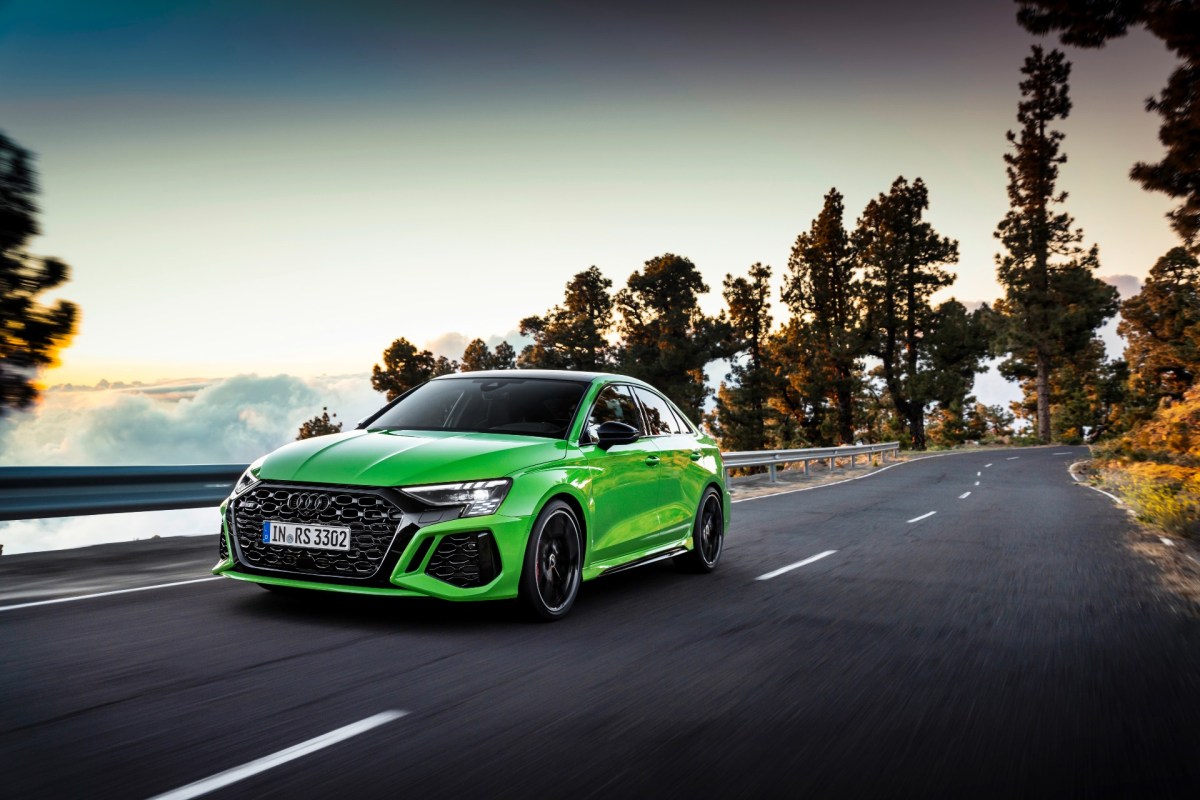 A bright green 2022 Audi RS3 sedan driving on a mountain road.