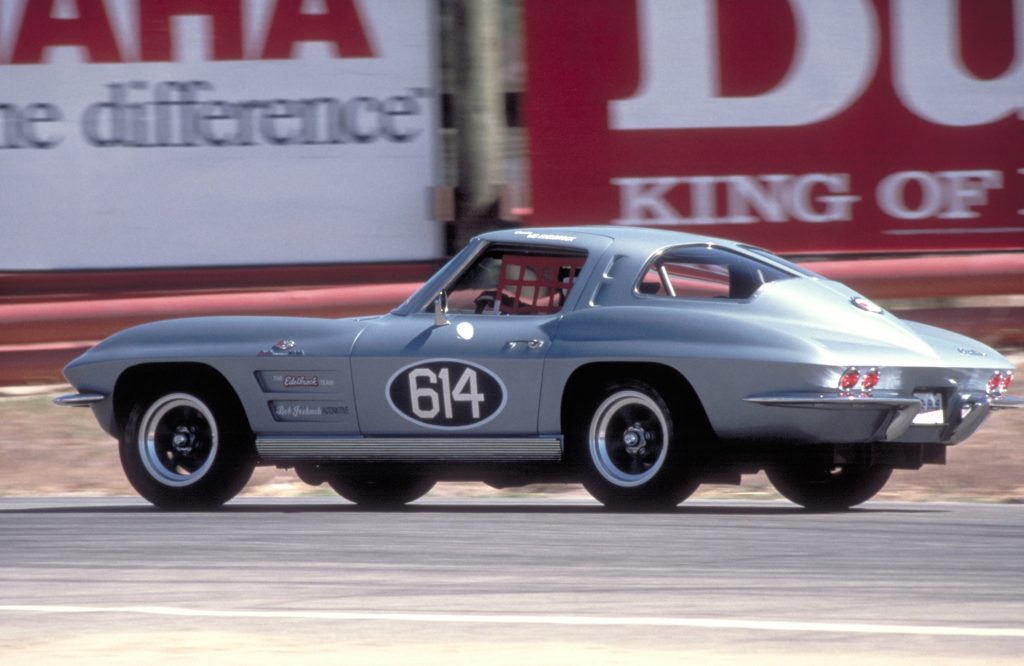 A blue-and-white racing-spec 1963 C2 Chevrolet Corvette Z06 goes around a track
