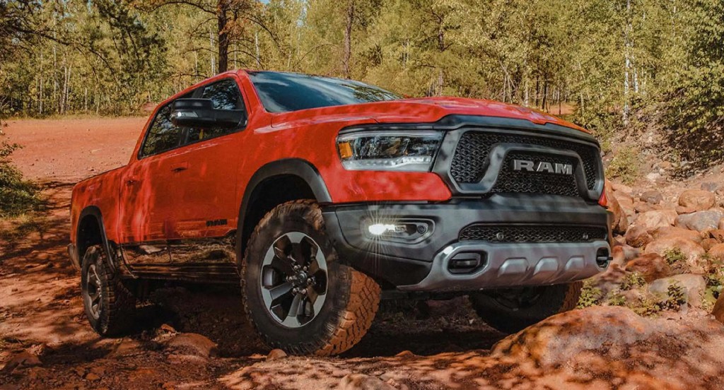 A red Ram 1500 is driving in a rocky area. 
