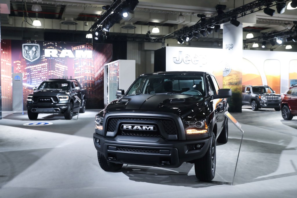 Black Ram truck with others behind it, possibly a Ram 1500, in an indoor environment. 