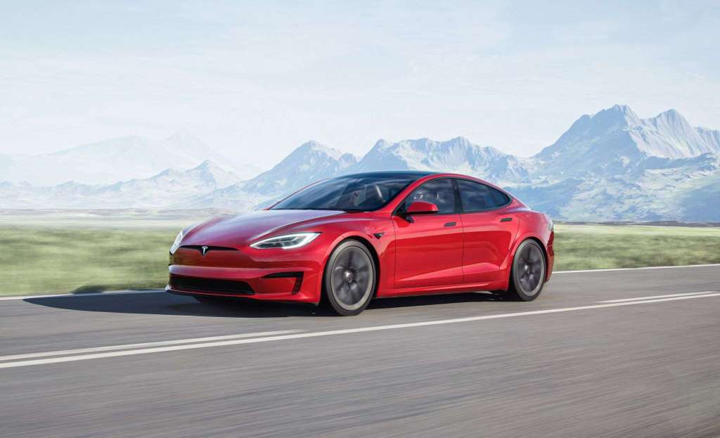 Red Tesla Model S driving, highlighting how EV car batteries destroy the environment and violate human rights