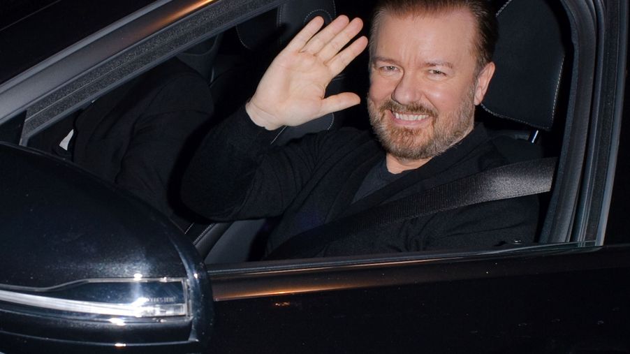 Ricky Gervais waving from a black car.