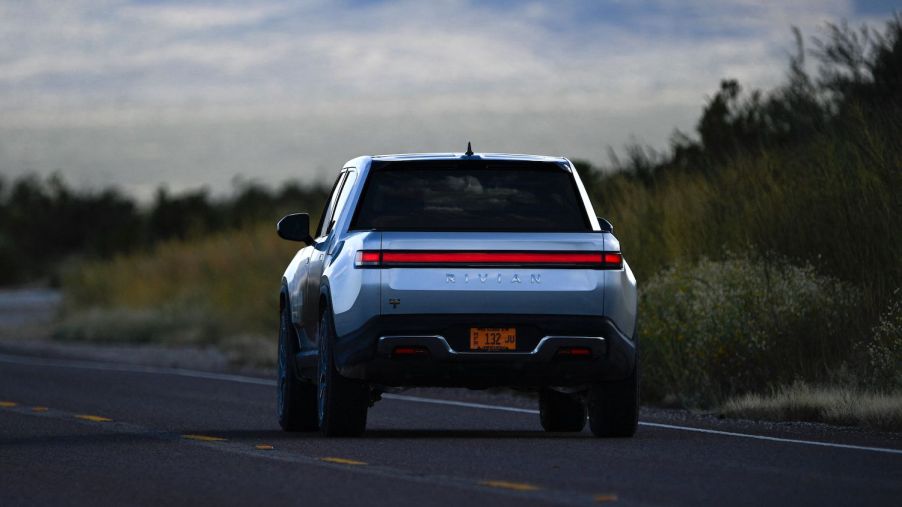 A silver Rivian R1T electric pickup driving on the highway.