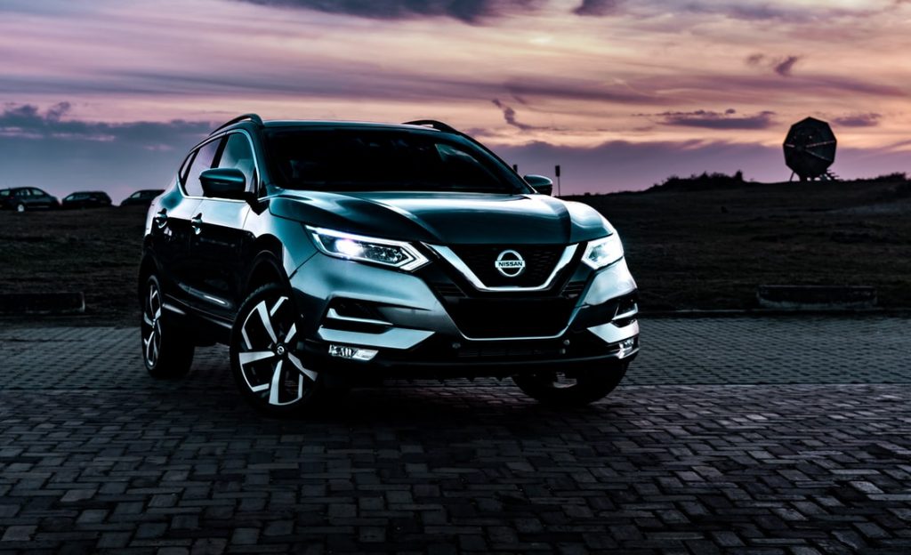 A dark colored 2022 Nissan Rogue Sport with a sunset i the background.