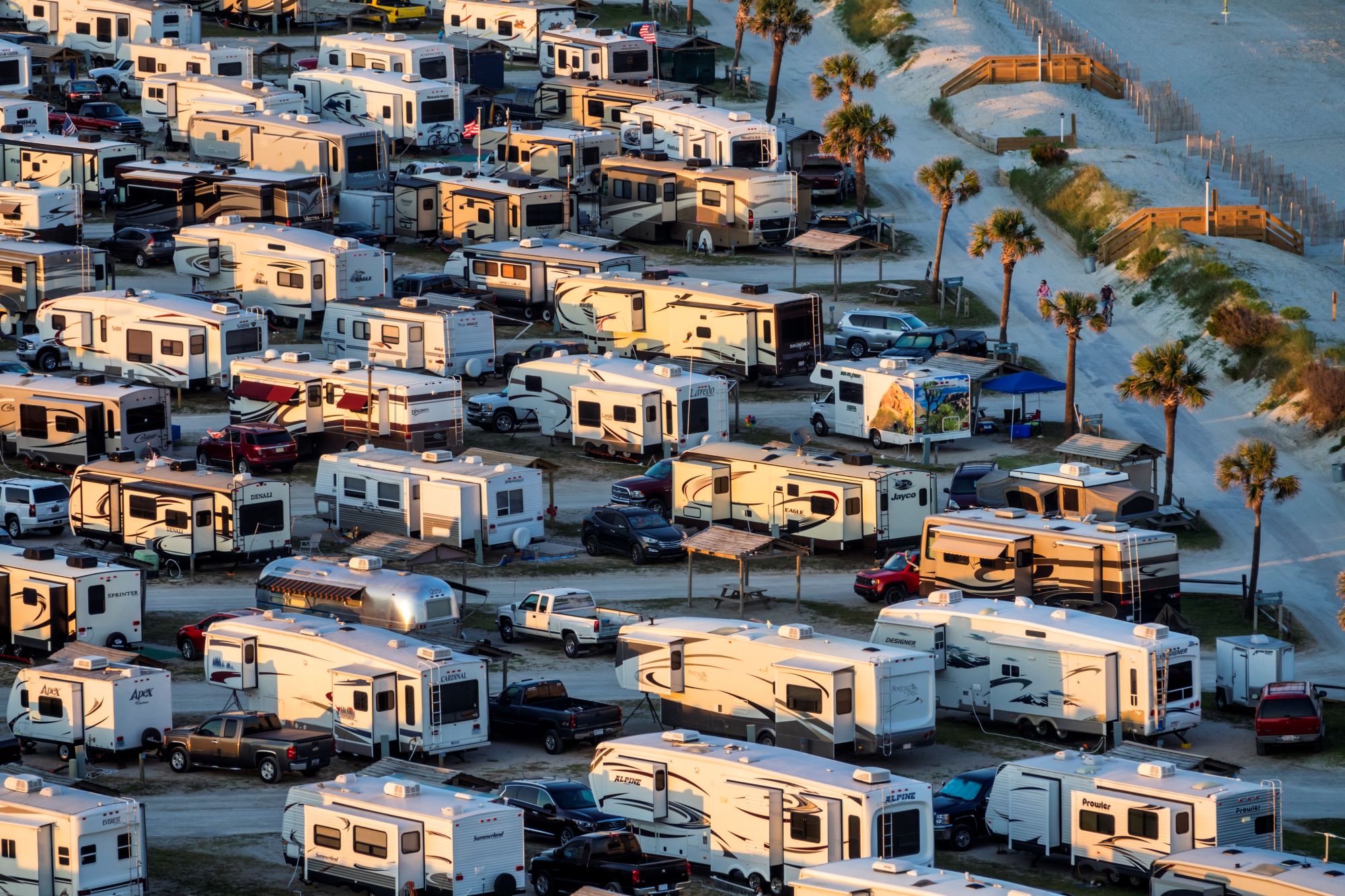 Rows of RV travel trailers next to the ocean. 