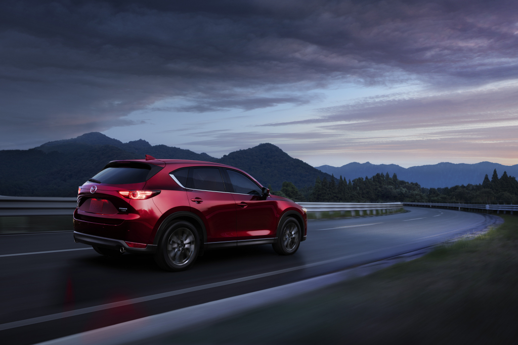 Soul Red Crystal Metallic 2022 Mazda CX-5 driving on a highway with mountains in the background