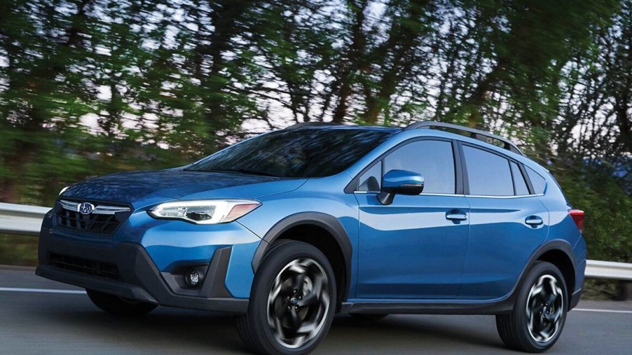 A blue 2022 Subaru Crosstrek Limited is driving on the road.