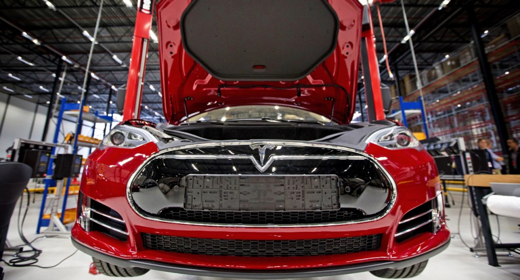 A red Tesla electric vehicle is being assembled.