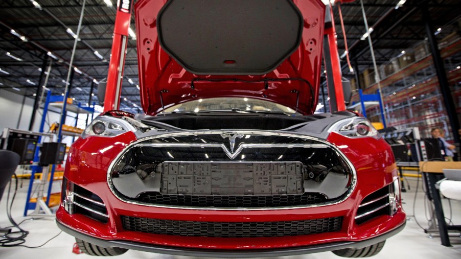 A red Tesla electric vehicle is being assembled.