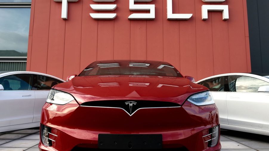 A red Tesla Model 3 in front of one of the brand's showrooms