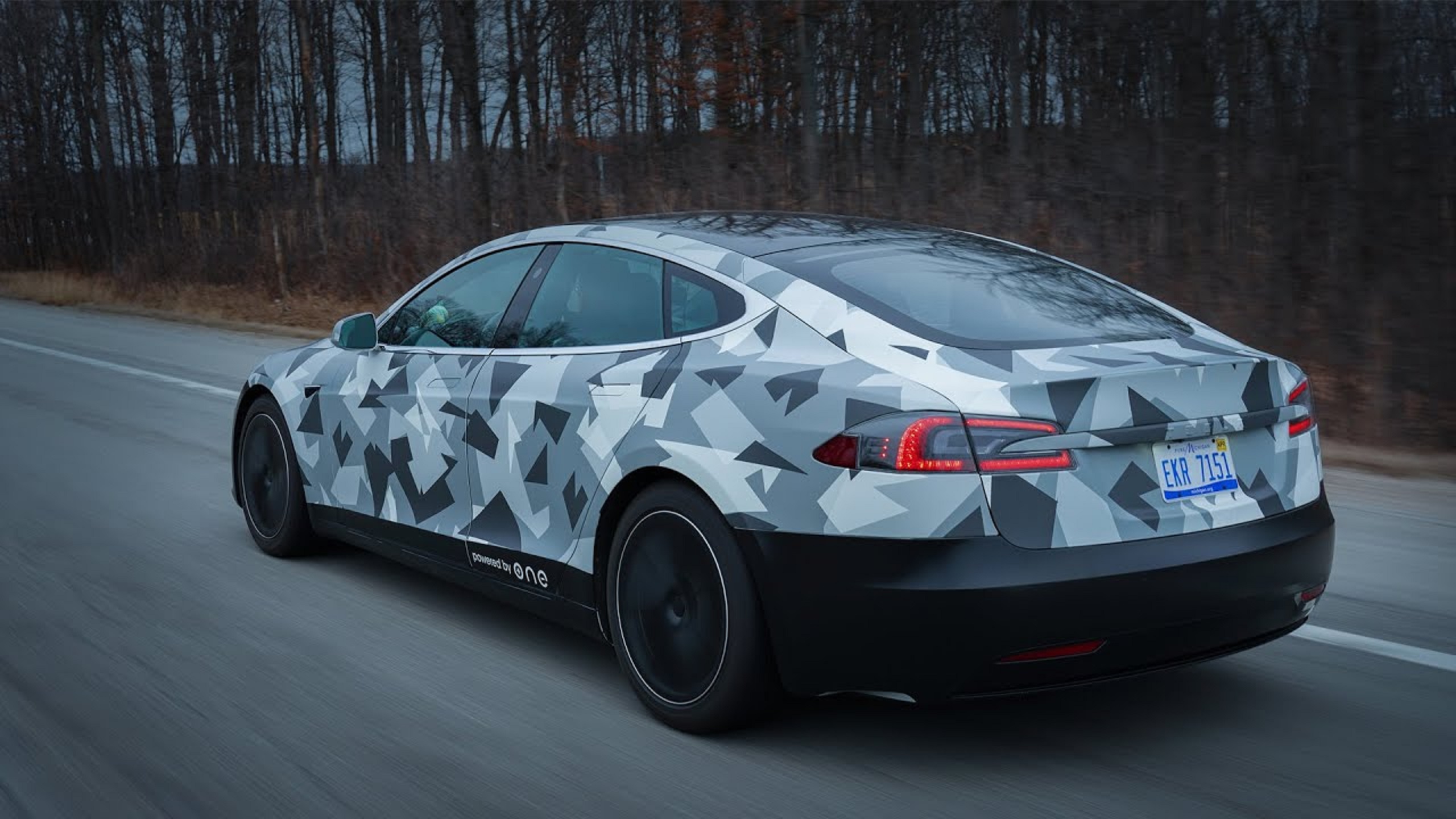 A black-white-and-gray-camo Tesla Model S Long Range Plus with ONE Gemini battery pack on a Michigan road