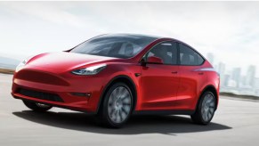 A red Tesla Model Y is driving on the road.