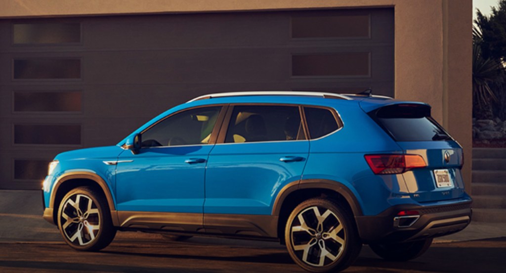 A blue 2022 Volkswagen Taos subcompact SUV is parked outside of a home. 