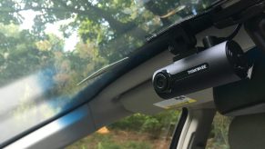 A Thinkware F70 dashcam mounted behind a rearview mirror in a car