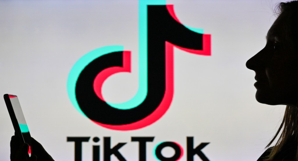 An image of a woman holding a cell phone in front of a TikTok logo.