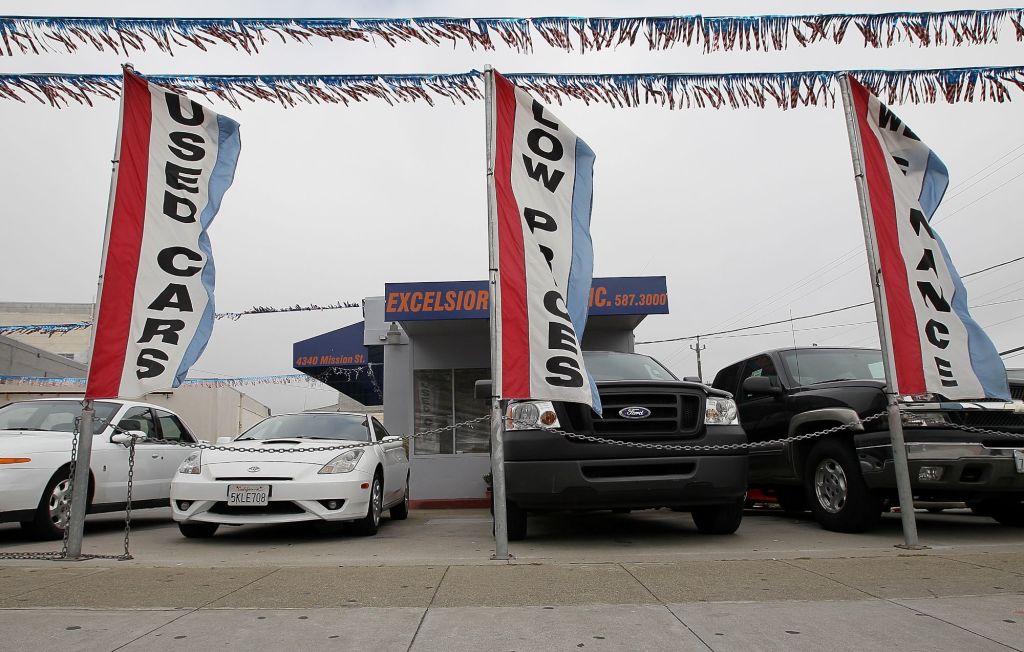 A used car dealership with flags and various cars out front.