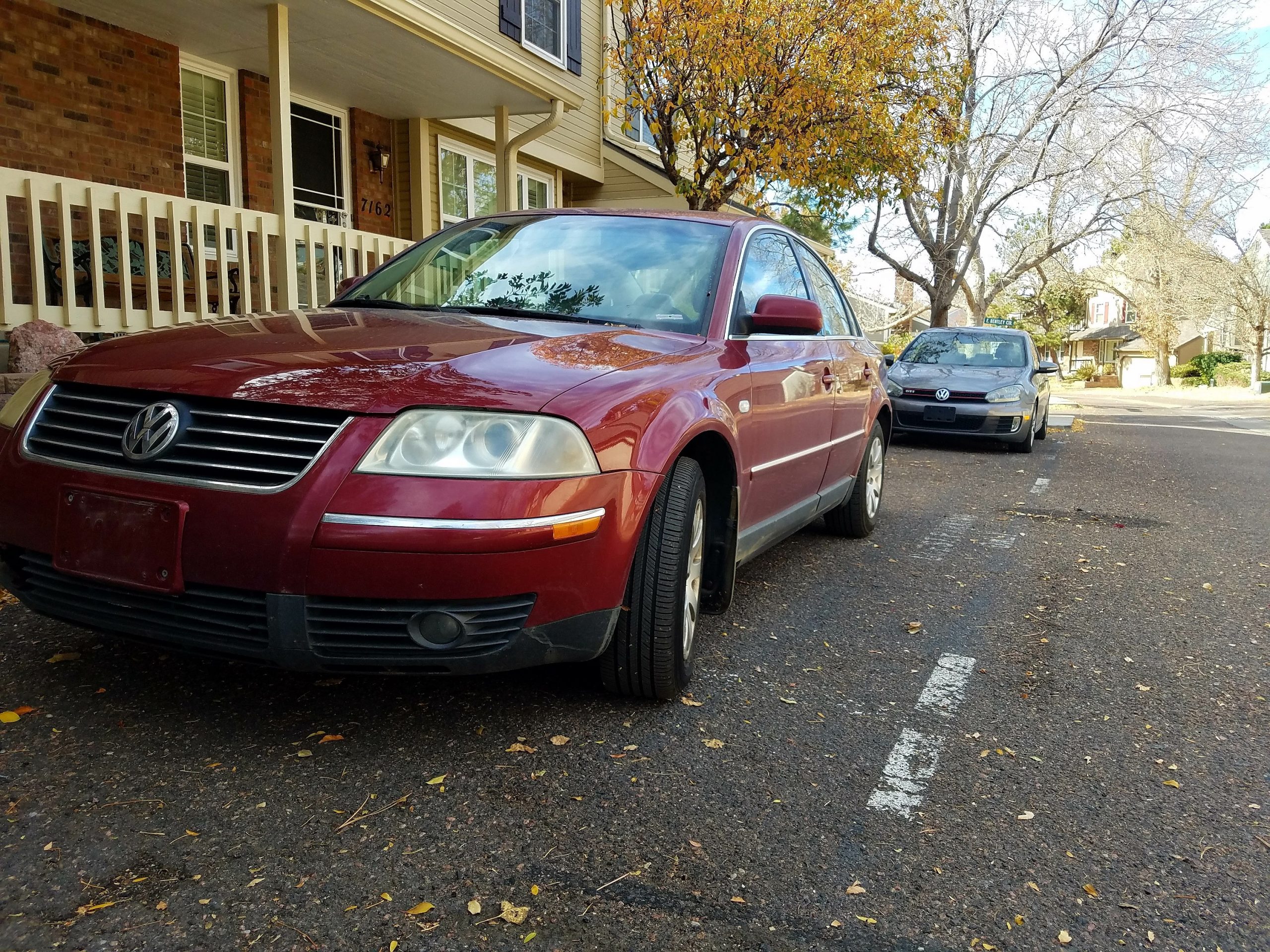 A maroon 2003 Volkswagen Passat shot from the front 3/4 with a silver GTI in the background