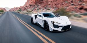 W Motors Fenyr SuperSport supercar in white driving down a country highway near red rock cliffs