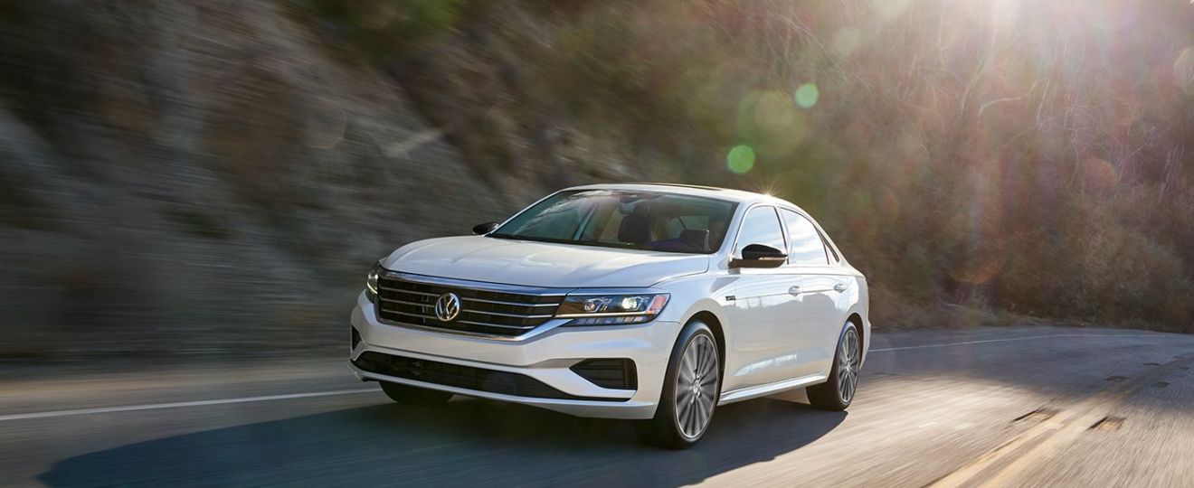 White 2022 VW Passat sedan, which Volkswagen killed off in all contries, driving by a forest