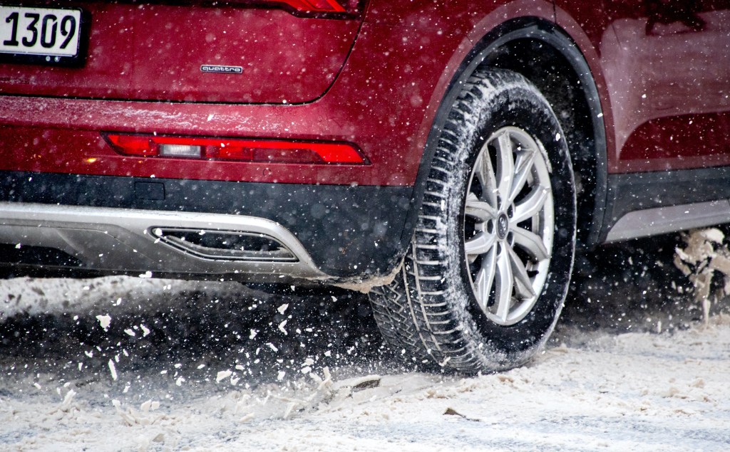 A car's tire spins on an icy and snow-covered road.