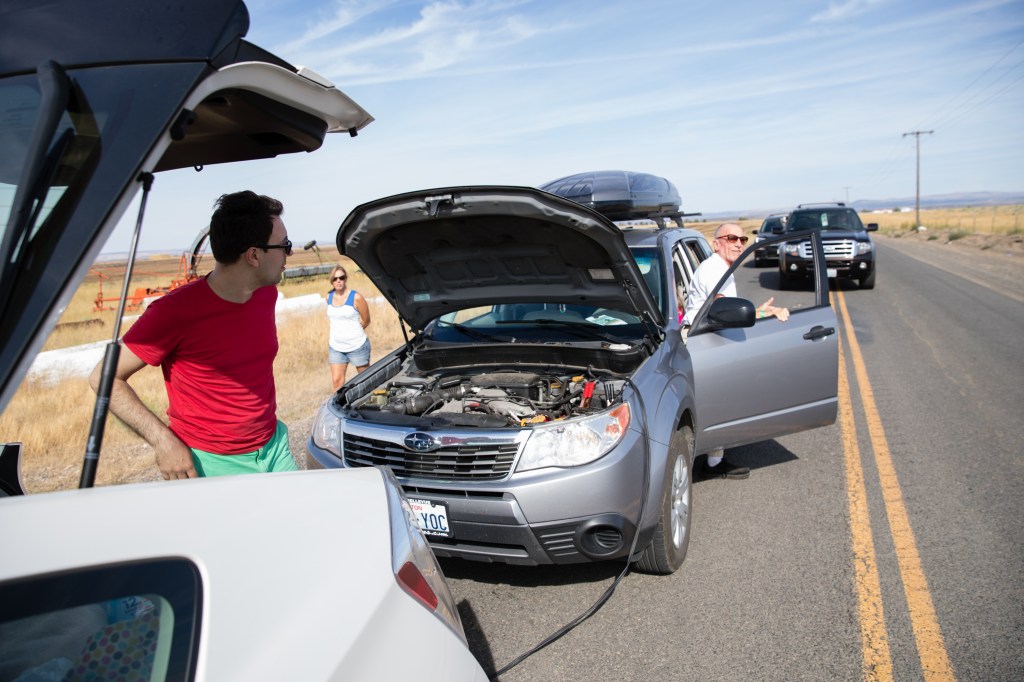 A driver of a Toyota Prius helps jump-start the dead battery on a Subaru vehicle.