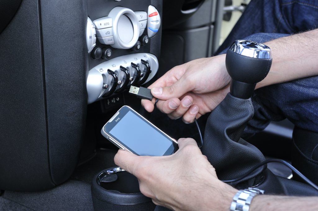 A mobile phone is plugged into a car with a USB cable.