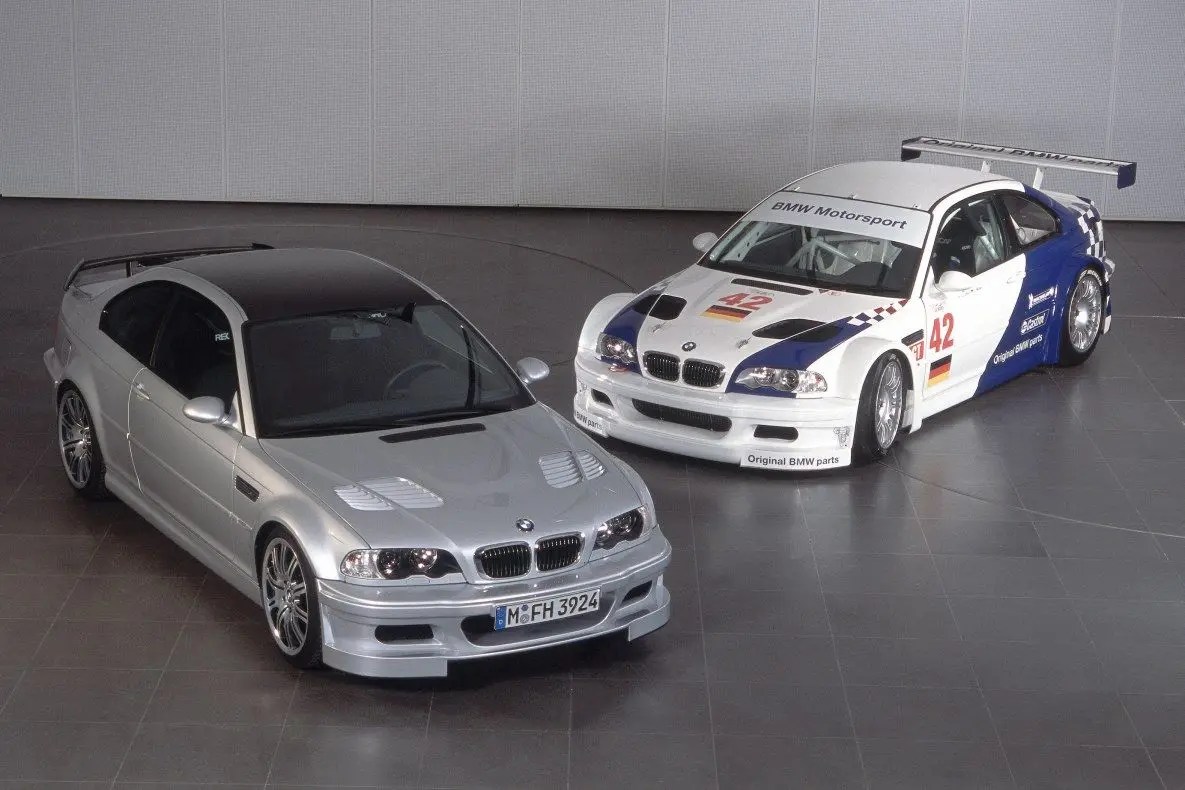 A silver BMW M3 GTR next to the racing version.